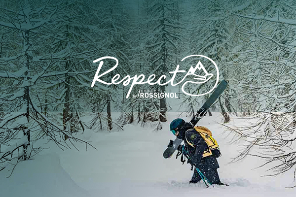 A man carrying his skis through a snowy forest