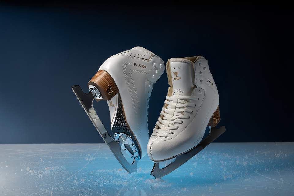 A close-up of ice skates suspended above the ice, set against a blue backdrop.