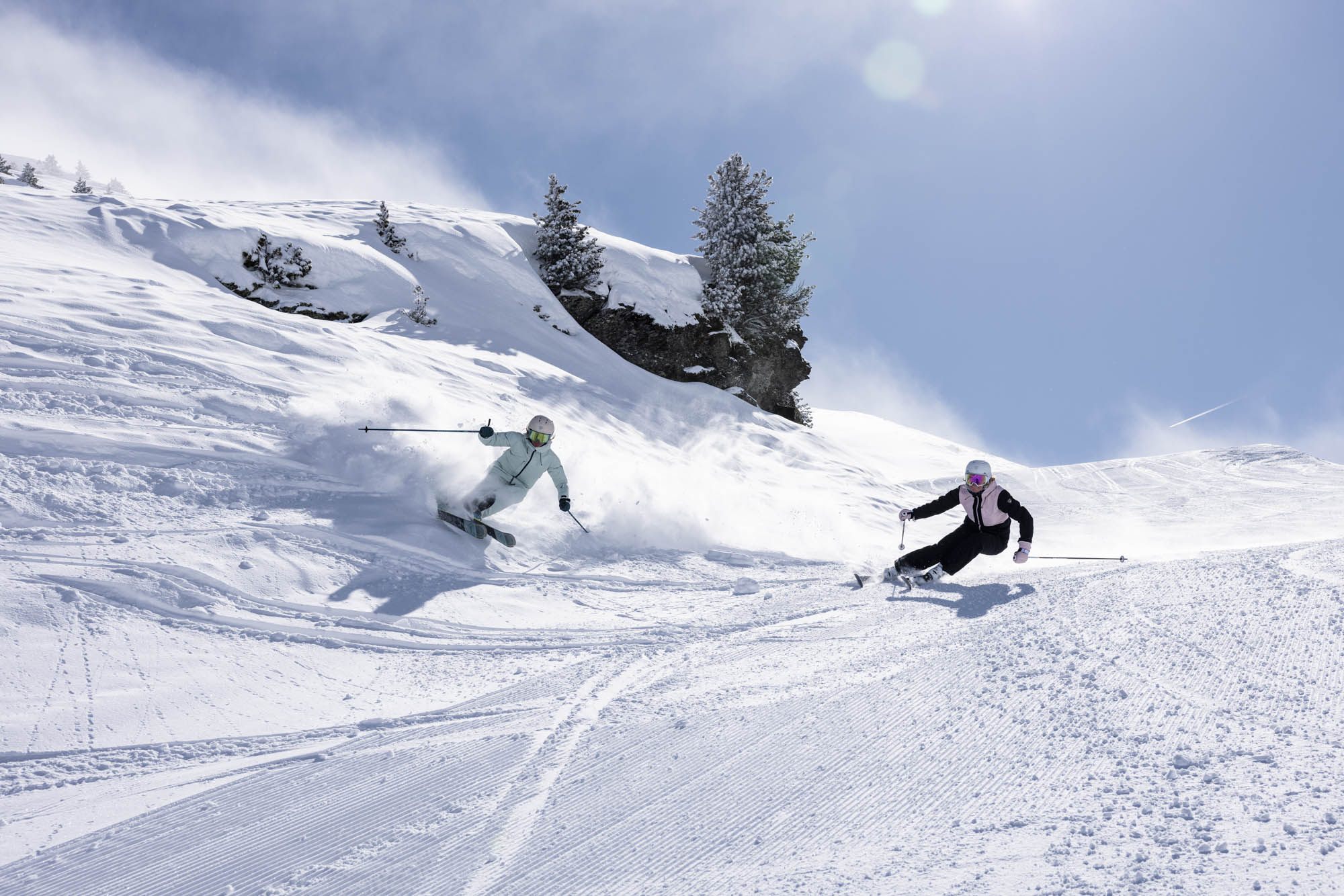 Deux personnes en ski portant des tenues Rossignol, ils skient avec les Arcade, parfait pour les différents type de neige trouvable en montagne.